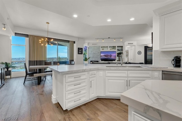 kitchen with white cabinets, a notable chandelier, light stone counters, and light hardwood / wood-style floors