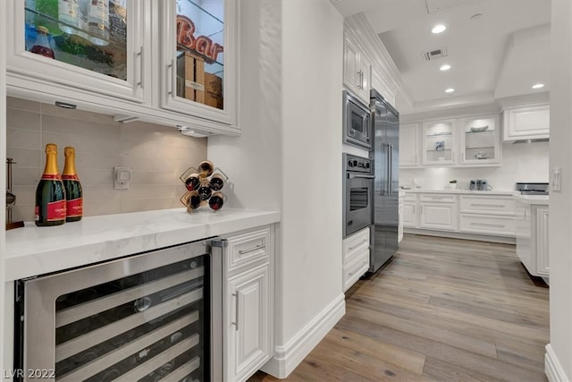 kitchen featuring white cabinets, built in appliances, and light wood-type flooring