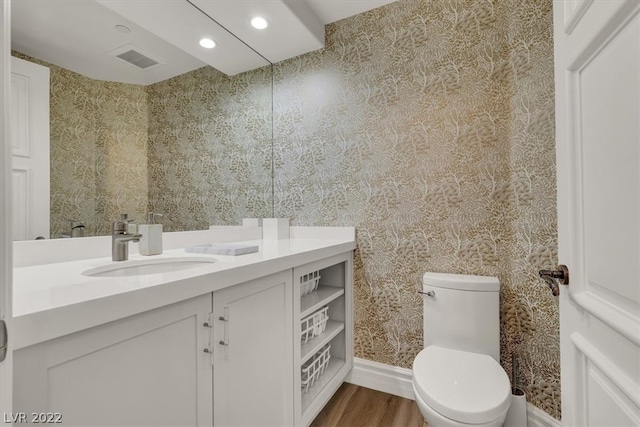 bathroom featuring toilet, vanity with extensive cabinet space, and hardwood / wood-style floors