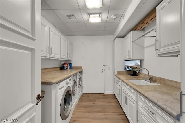 clothes washing area with cabinets, independent washer and dryer, sink, and light hardwood / wood-style flooring