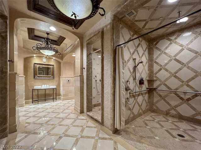 hallway featuring crown molding, a raised ceiling, light tile flooring, and tile walls