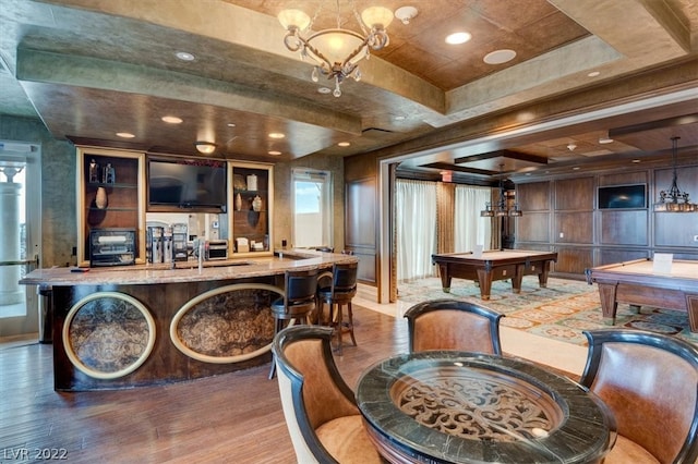 dining area with wood-type flooring, a chandelier, a tray ceiling, and billiards