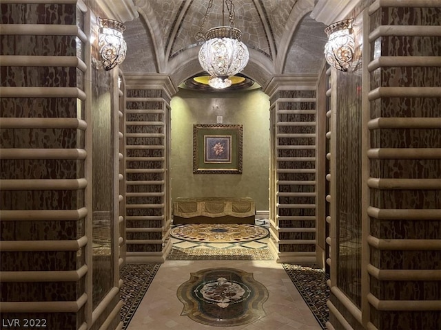 wine room featuring lofted ceiling, tile flooring, and a notable chandelier