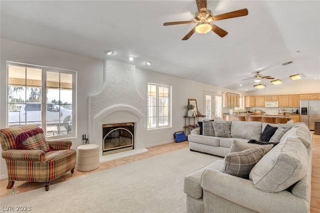 living room with a large fireplace, ceiling fan, light tile patterned floors, and a healthy amount of sunlight