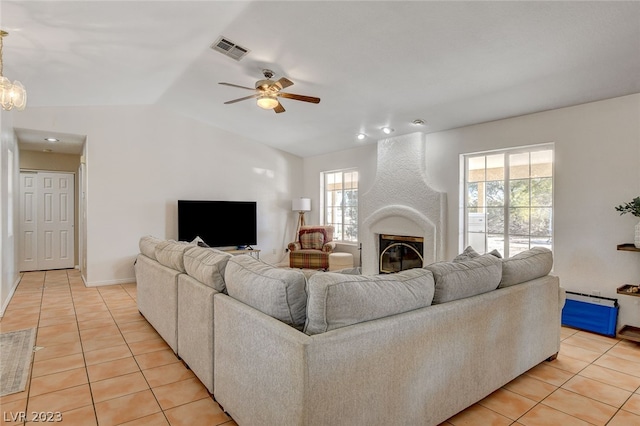 tiled living room with lofted ceiling, ceiling fan, and a fireplace