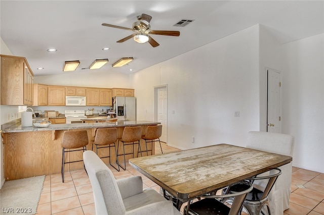 tiled dining space with lofted ceiling and ceiling fan