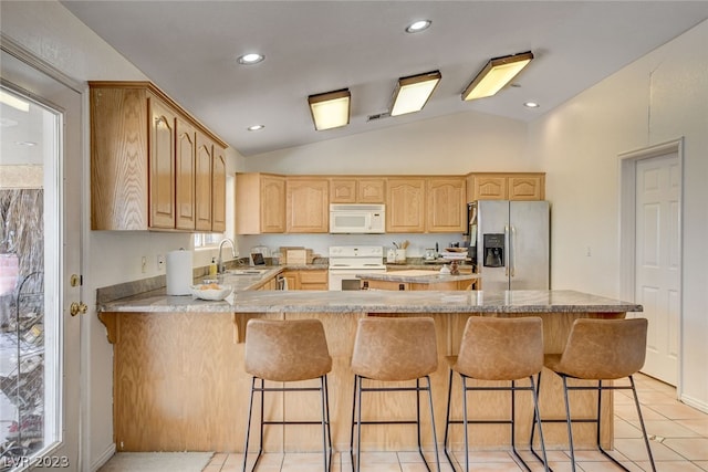 kitchen with white appliances, a kitchen breakfast bar, kitchen peninsula, sink, and vaulted ceiling