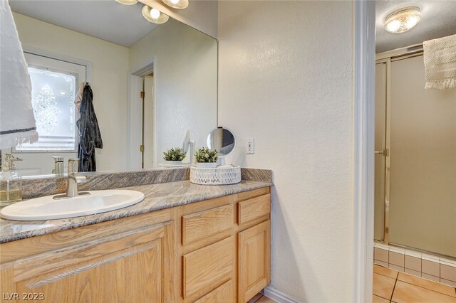 bathroom featuring tile patterned flooring, a shower with door, and vanity