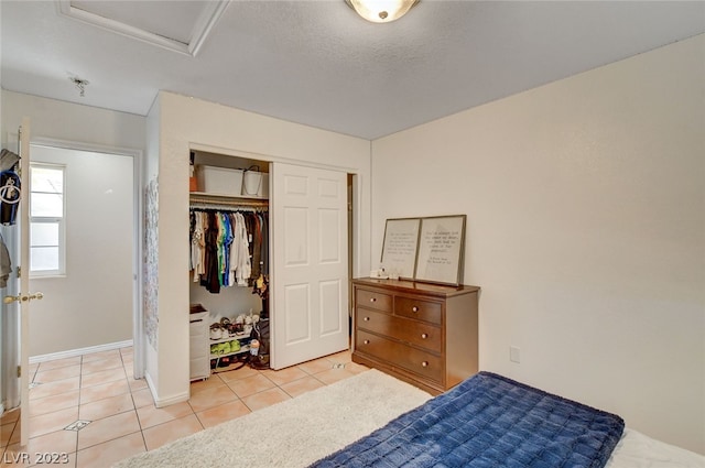 bedroom featuring a textured ceiling, light tile patterned floors, and a closet