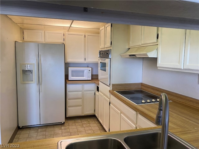 kitchen featuring white cabinets, white appliances, sink, and light tile floors