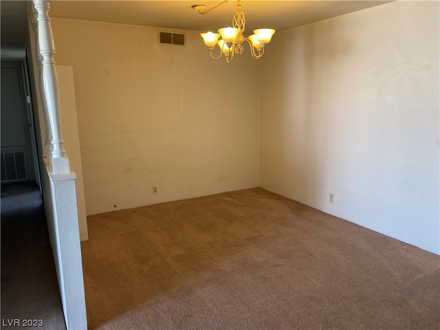 carpeted spare room with an inviting chandelier