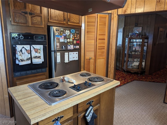 kitchen featuring carpet flooring, appliances with stainless steel finishes, custom range hood, and wooden walls