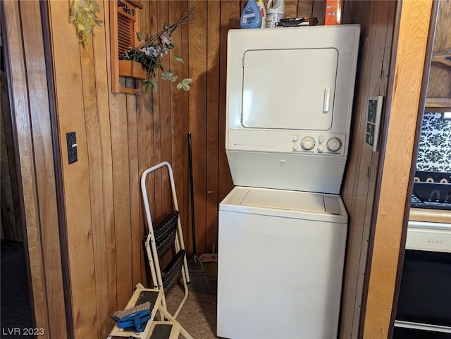 clothes washing area with wood walls and stacked washer and dryer