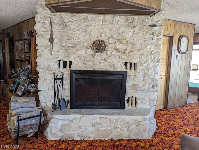 room details with carpet, wood walls, a stone fireplace, and a textured ceiling