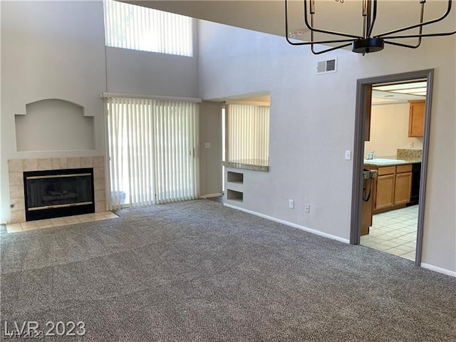 unfurnished living room with light colored carpet, a chandelier, and a high ceiling