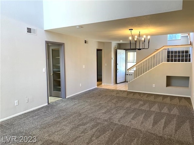 unfurnished living room with light carpet, a chandelier, and a towering ceiling