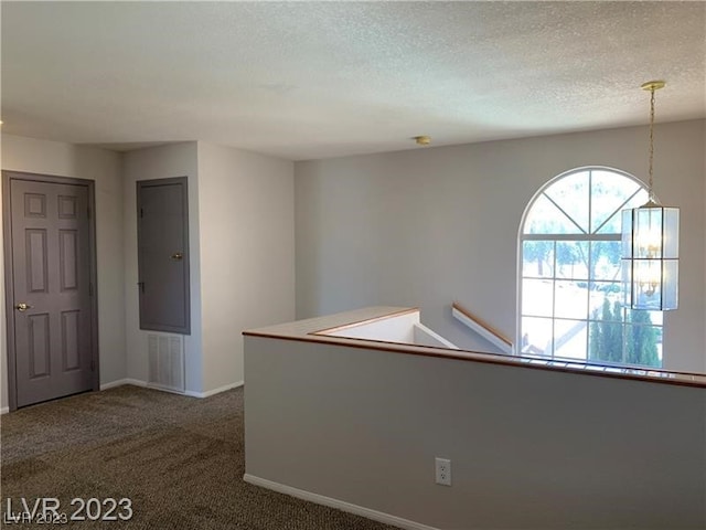 hallway featuring dark colored carpet and a textured ceiling