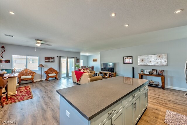 kitchen with ceiling fan, a kitchen island, and light hardwood / wood-style floors