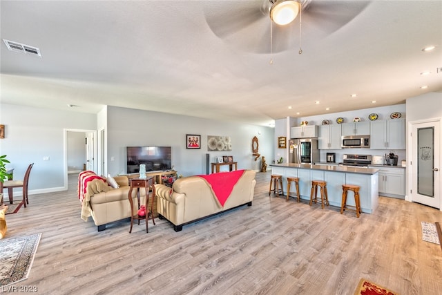 living room featuring ceiling fan and light wood-type flooring