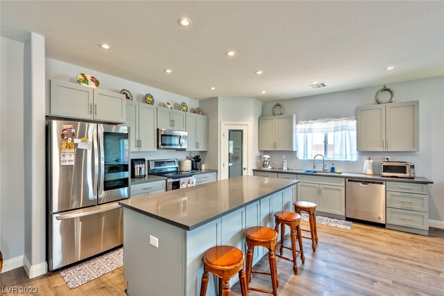 kitchen with a kitchen bar, a kitchen island, appliances with stainless steel finishes, and light wood-type flooring