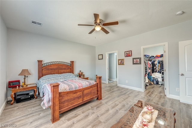 bedroom featuring a spacious closet, a closet, ceiling fan, and light wood-type flooring