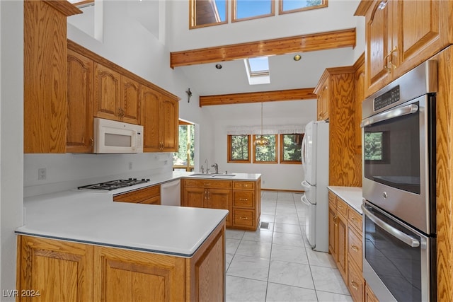 kitchen with beamed ceiling, white appliances, kitchen peninsula, sink, and hanging light fixtures