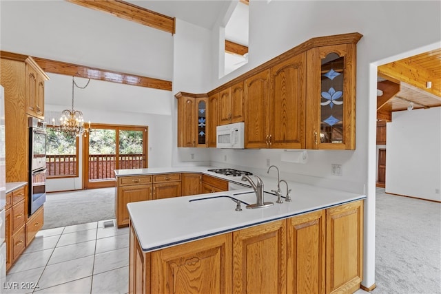 kitchen with a notable chandelier, white appliances, light carpet, and kitchen peninsula