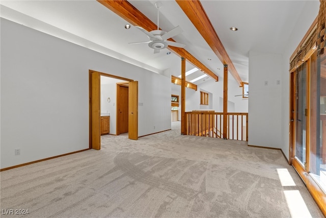 spare room with ceiling fan, light carpet, and beam ceiling