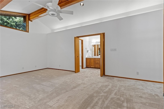 unfurnished bedroom with light colored carpet, connected bathroom, ceiling fan, and lofted ceiling with beams