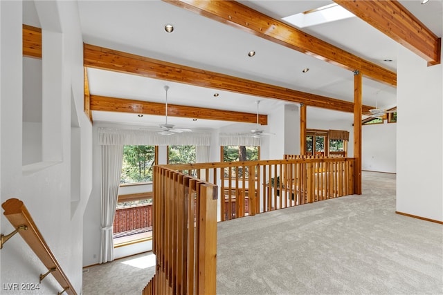 interior space with ceiling fan, beam ceiling, and light carpet