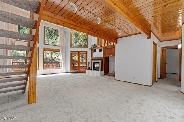 unfurnished living room with a fireplace, wooden ceiling, light colored carpet, beamed ceiling, and track lighting