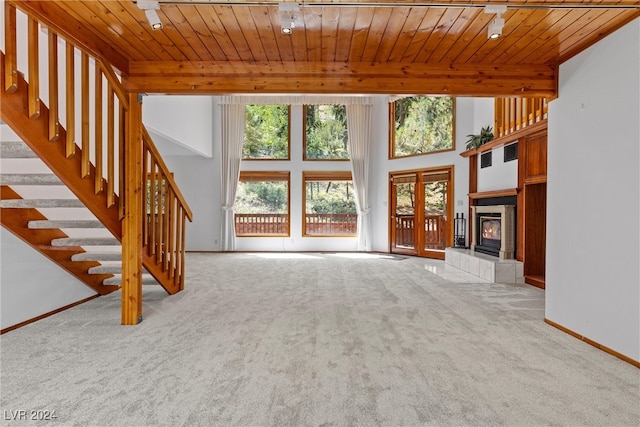 unfurnished living room featuring a fireplace, light colored carpet, and wooden ceiling