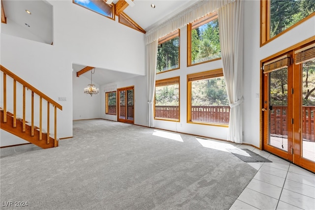 unfurnished living room with light carpet, high vaulted ceiling, and a notable chandelier