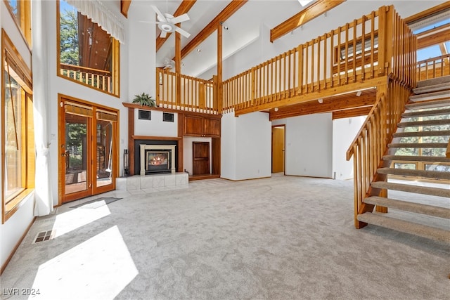 living room featuring a healthy amount of sunlight, ceiling fan, a high ceiling, and a tile fireplace