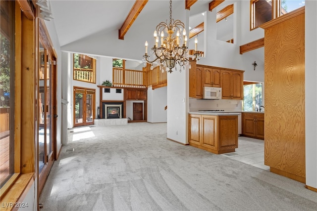 kitchen with a wealth of natural light, an inviting chandelier, light carpet, and beamed ceiling