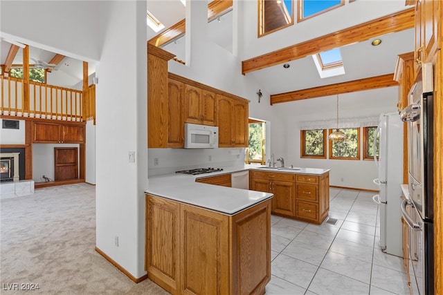 kitchen with a wealth of natural light, high vaulted ceiling, kitchen peninsula, and white appliances