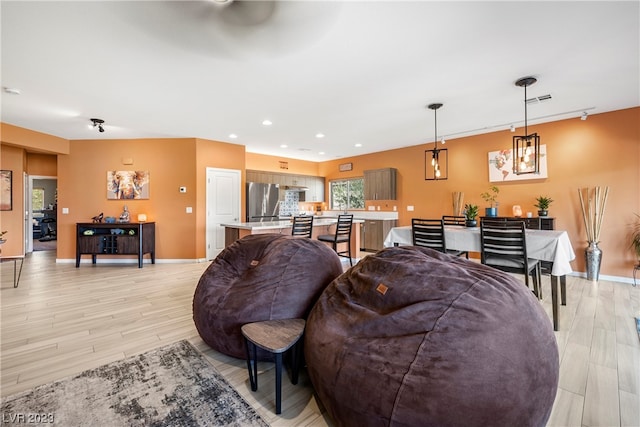 living room featuring light hardwood / wood-style floors and ceiling fan with notable chandelier