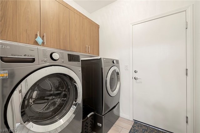 laundry area with cabinets, light hardwood / wood-style floors, and washing machine and dryer