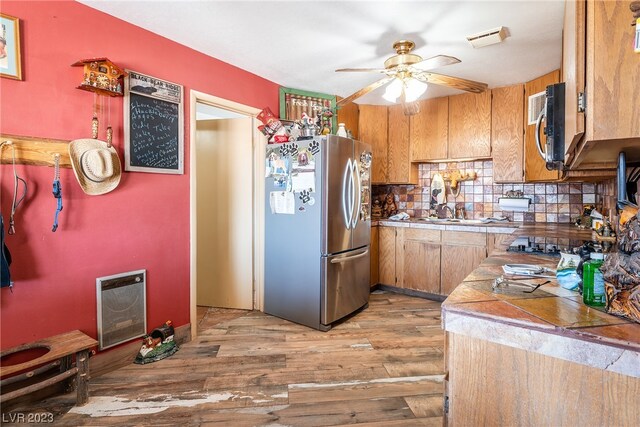 kitchen with ceiling fan, dark wood-type flooring, appliances with stainless steel finishes, and tasteful backsplash