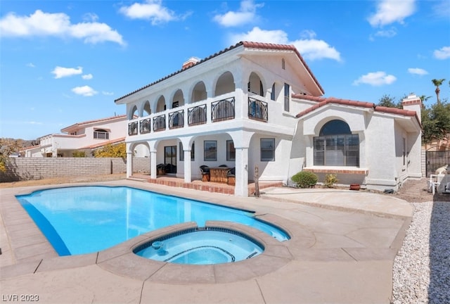 rear view of house featuring a balcony, a patio area, and a swimming pool with hot tub