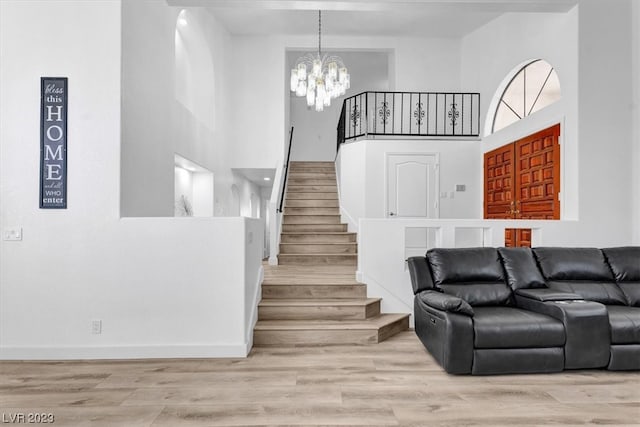 foyer featuring an inviting chandelier, light hardwood / wood-style floors, and a high ceiling