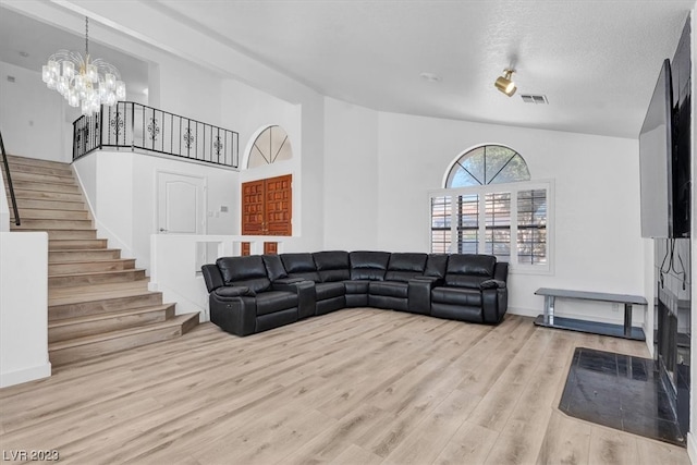 living room with a notable chandelier, a high ceiling, and light hardwood / wood-style flooring