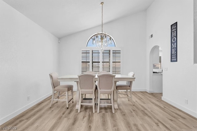 dining space featuring a notable chandelier, light wood-type flooring, and high vaulted ceiling