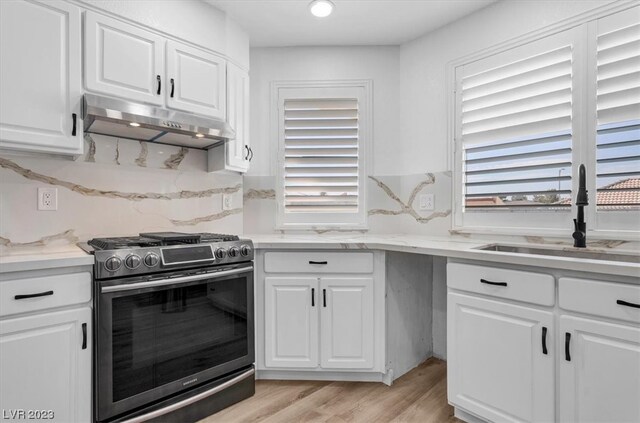 kitchen with white cabinetry, sink, gas range, and light hardwood / wood-style floors