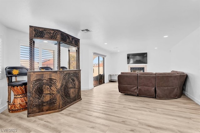 living room featuring a brick fireplace and light wood-type flooring