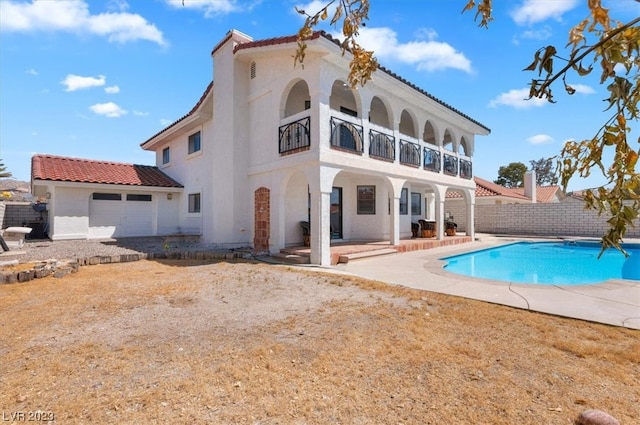 back of house with a balcony, a fenced in pool, and a patio area