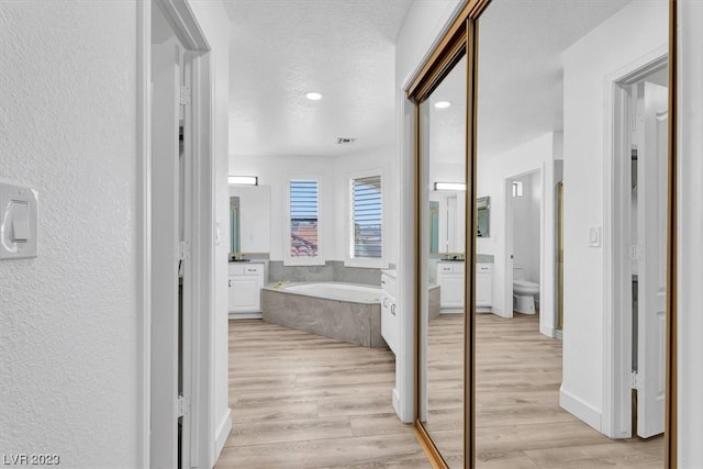 hall featuring light hardwood / wood-style flooring and a textured ceiling