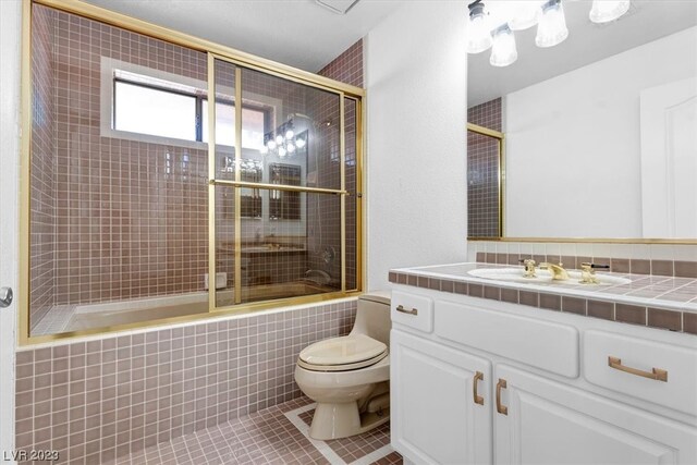 full bathroom featuring toilet, tile flooring, vanity, backsplash, and combined bath / shower with glass door