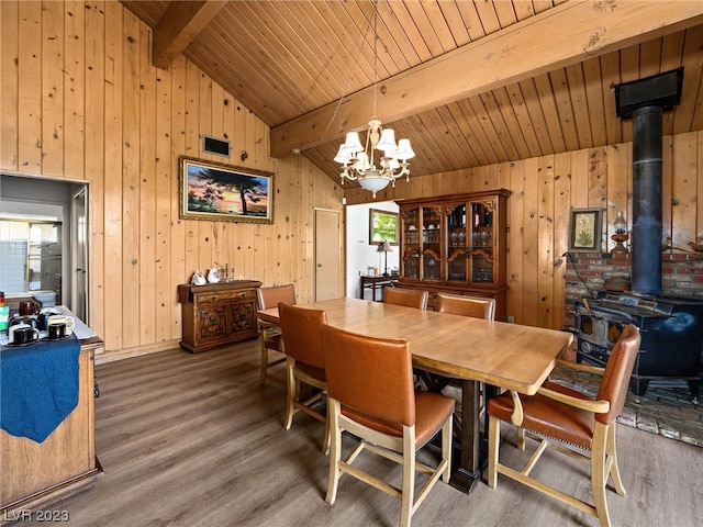 dining room with a notable chandelier, wood ceiling, a wood stove, dark hardwood / wood-style floors, and lofted ceiling with beams