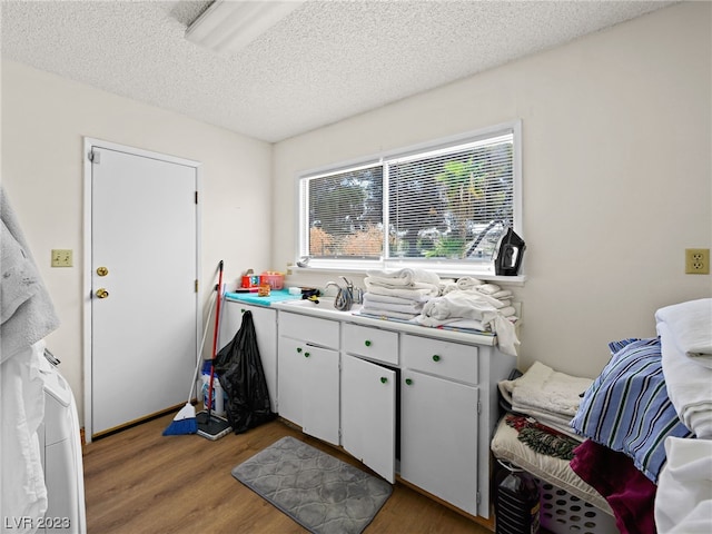 kitchen featuring a textured ceiling, wood-type flooring, white cabinets, and sink